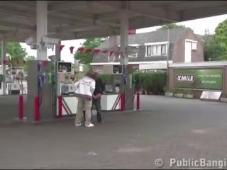 Veldig gravid lover offentlig trekant ved en gas stasjon